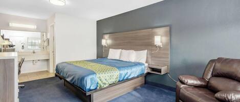 A hotel room with a bed, a desk, a chair, and a bathroom.