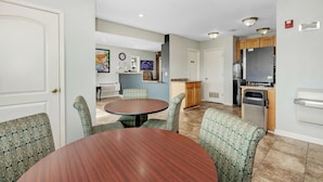 A dining area with a round table and four chairs, a kitchen with wooden cabinets, a refrigerator, and a microwave.