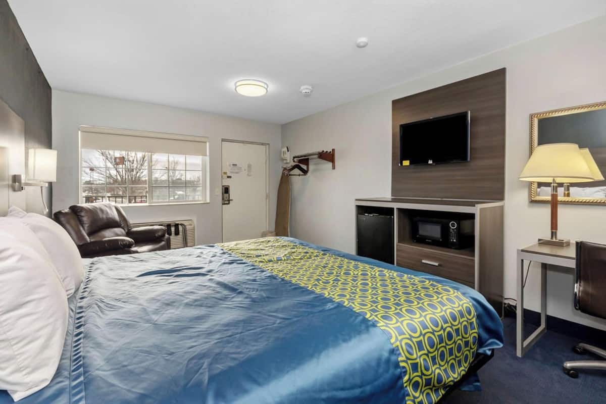A hotel room with a bed, a desk, a television, and a window.