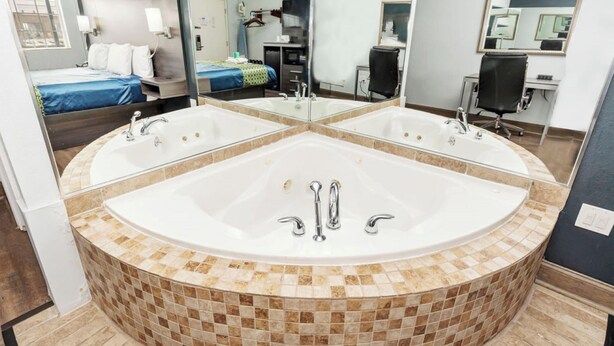 A modern bathroom with a large freestanding bathtub, a mirror, and a separate sink.