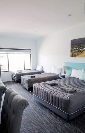 A hotel room with two beds, a sofa, a window, and a painting on the wall. - Robetown Motel (Robe)
