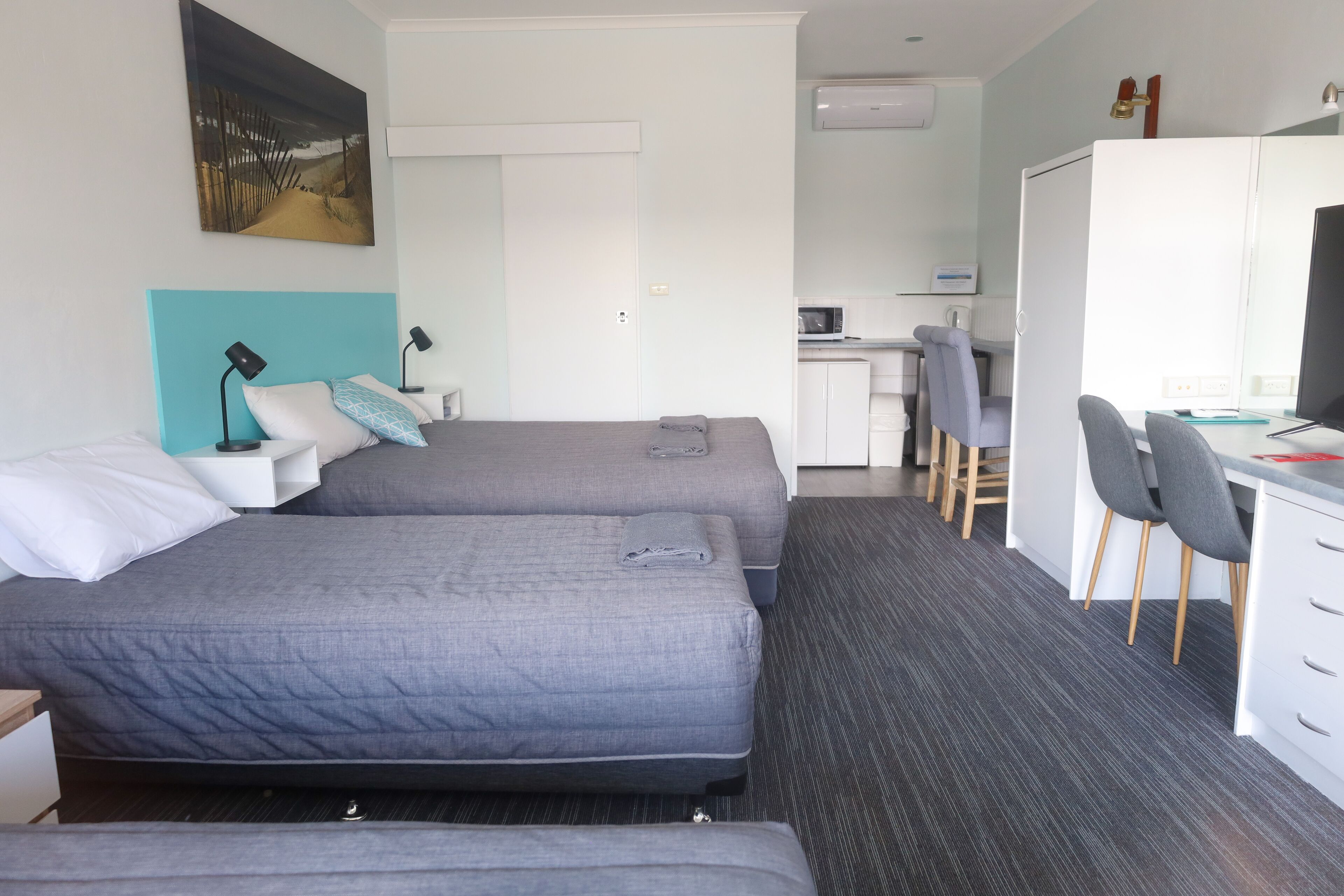 Una habitación de hotel con dos camas, un escritorio, una silla y un microondas.