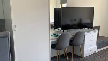 Una habitación moderna con escritorio, dos sillas, televisión de pantalla plana y armario.