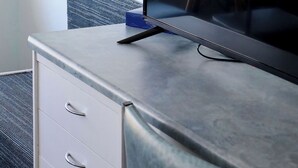 A modern hotel room with a large flat-screen TV on a marble desk, a white drawer unit, and a view of a parking lot through the window. - Robetown Motel (Robe)