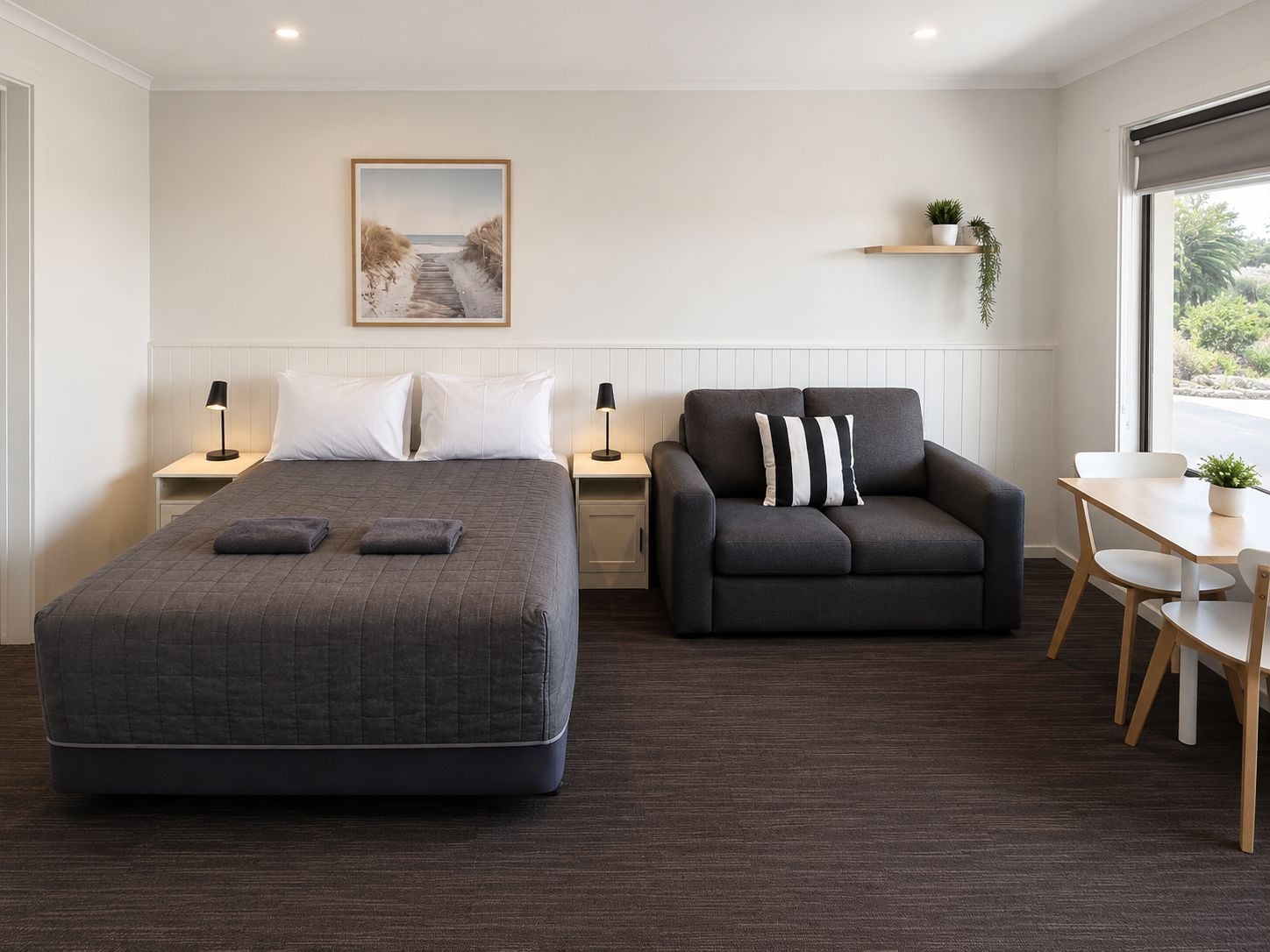 A bedroom with a bed, a sofa, a desk, and a window.