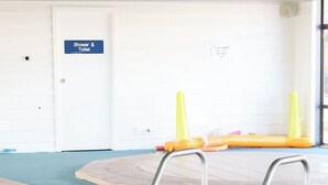 A swimming pool with metal ladders and a sign indicating a shower and toilet.