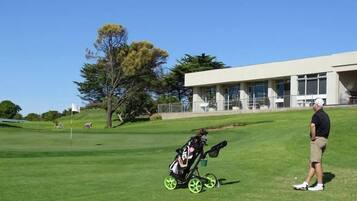 Un campo de golf con un edificio moderno al fondo.