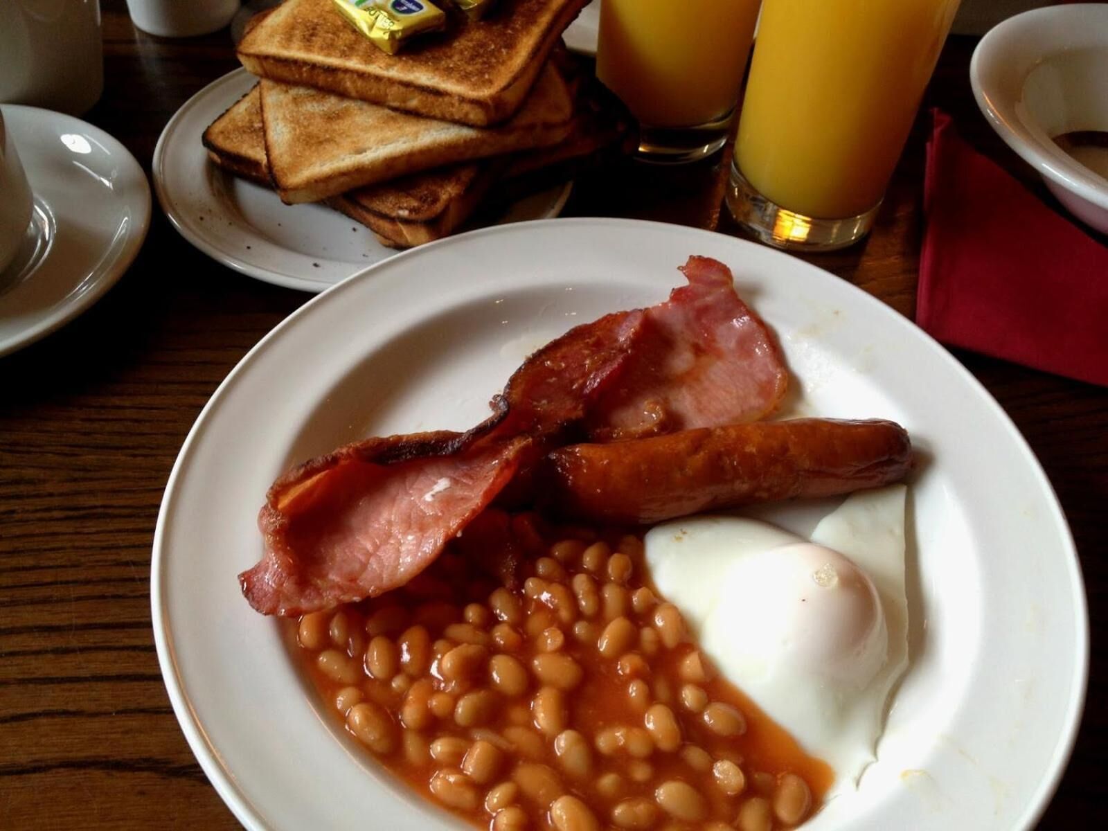 A plate of bacon, beans, and a fried egg.