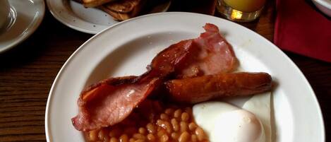A plate of bacon, beans, and a fried egg.