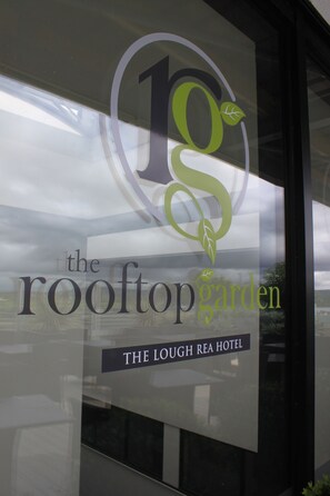 On peut voir une enseigne d’hôtel indiquant les noms « The Rooftop Garden » et « The Lough Rea Hotel ».