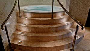 A spa area with a hot tub and a set of curved stairs with metal railings.