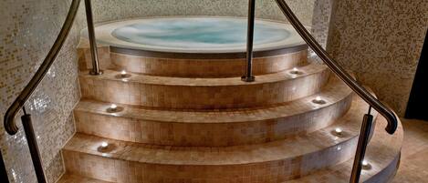 A spa area with a hot tub and a set of curved stairs with metal railings.