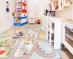 Um quarto infantil com um tapete colorido, brinquedos de madeira e prateleiras para guardar.