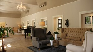 Un salón amplio con una suntuosa araña, un piano y un sofá beige grande.