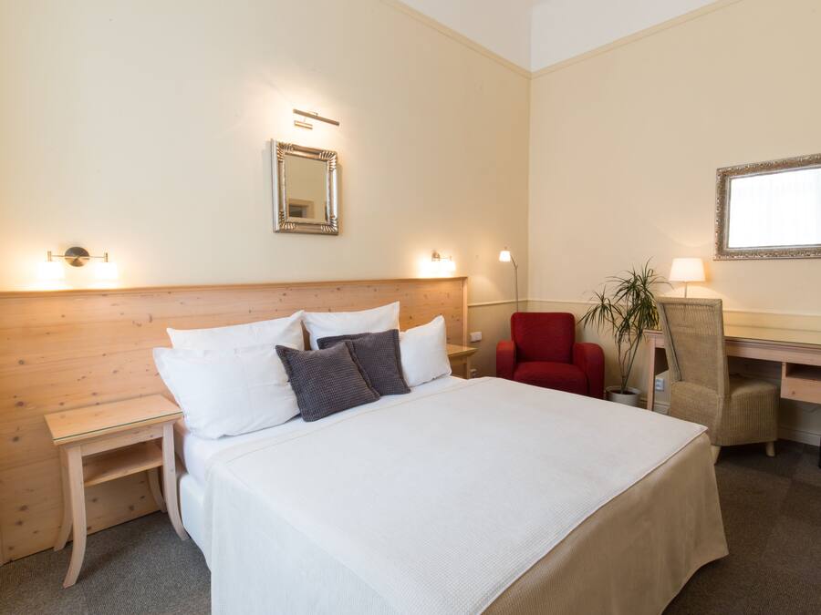 Une chambre d’hôtel avec un grand lit, un bureau, une chaise et une plante en pot.