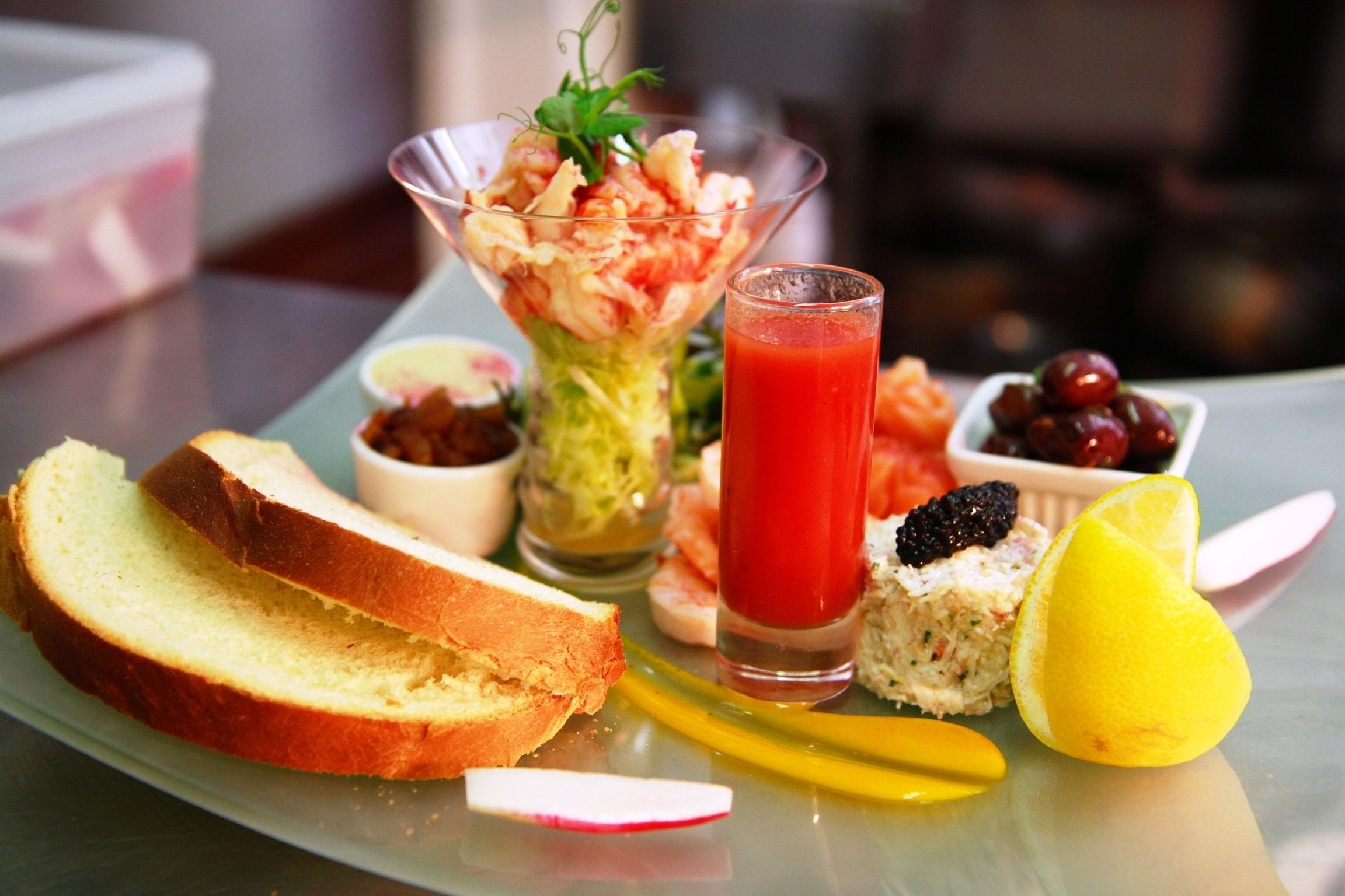 A meal with bread, a salad, a glass of red drink, and some fruit on a plate.