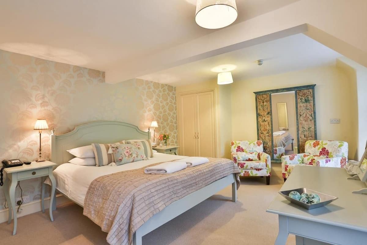 A bedroom with a bed, nightstands, a desk, and two chairs.
