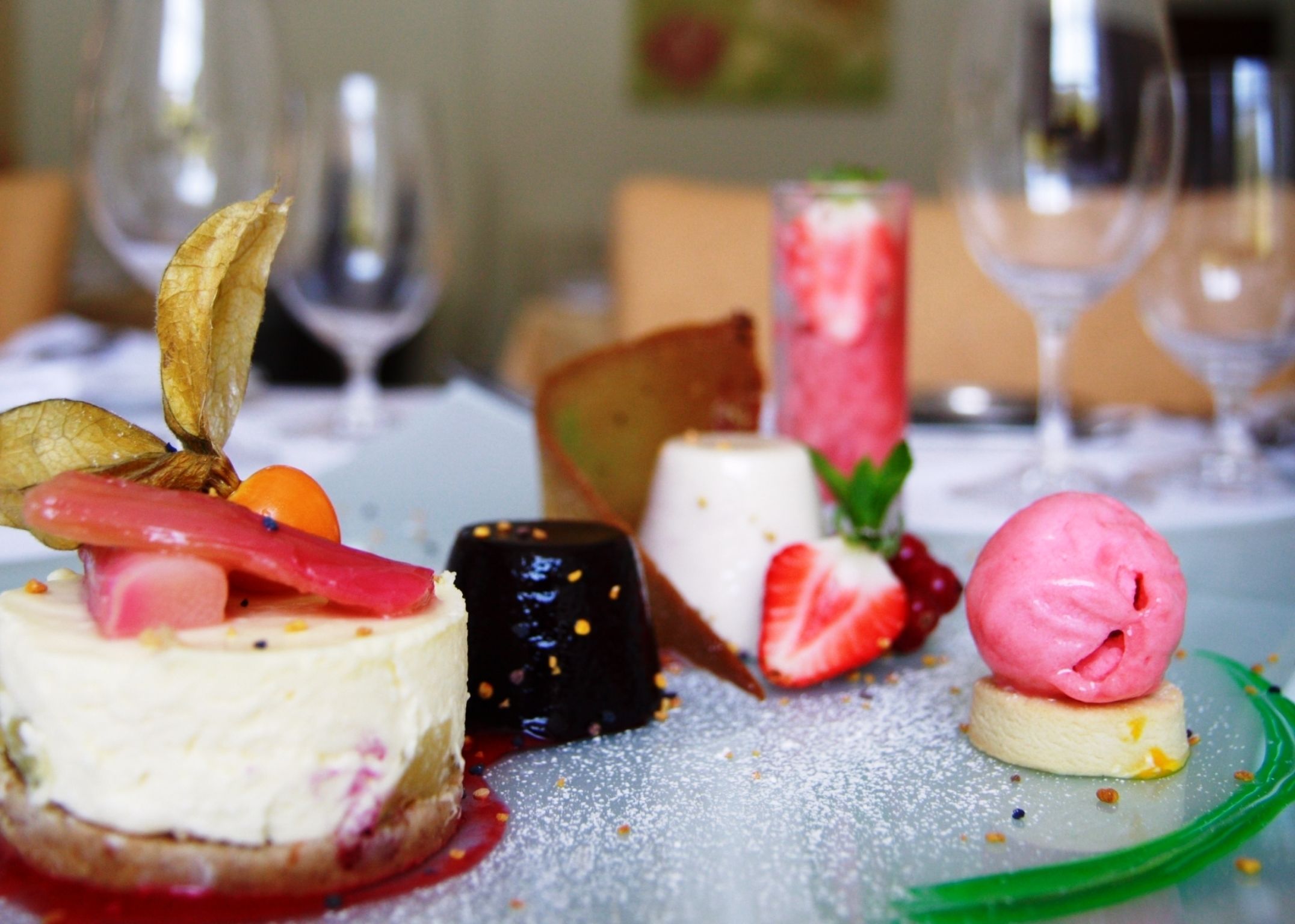 Een dessertbuffet met diverse taartjes, waaronder een cheesecake, iets met chocolade en roze ijs.