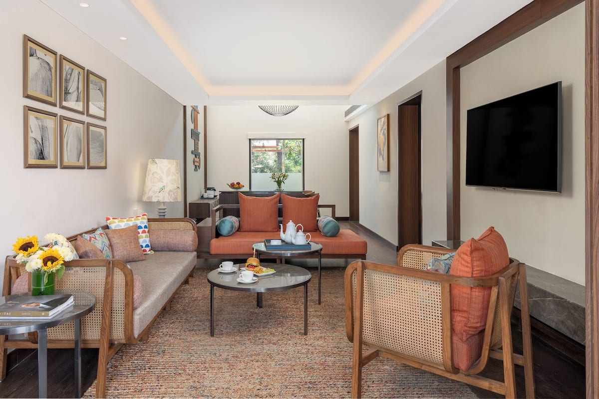 Una sala de estar con un sofá, dos sillones, una mesa de centro y un televisor.