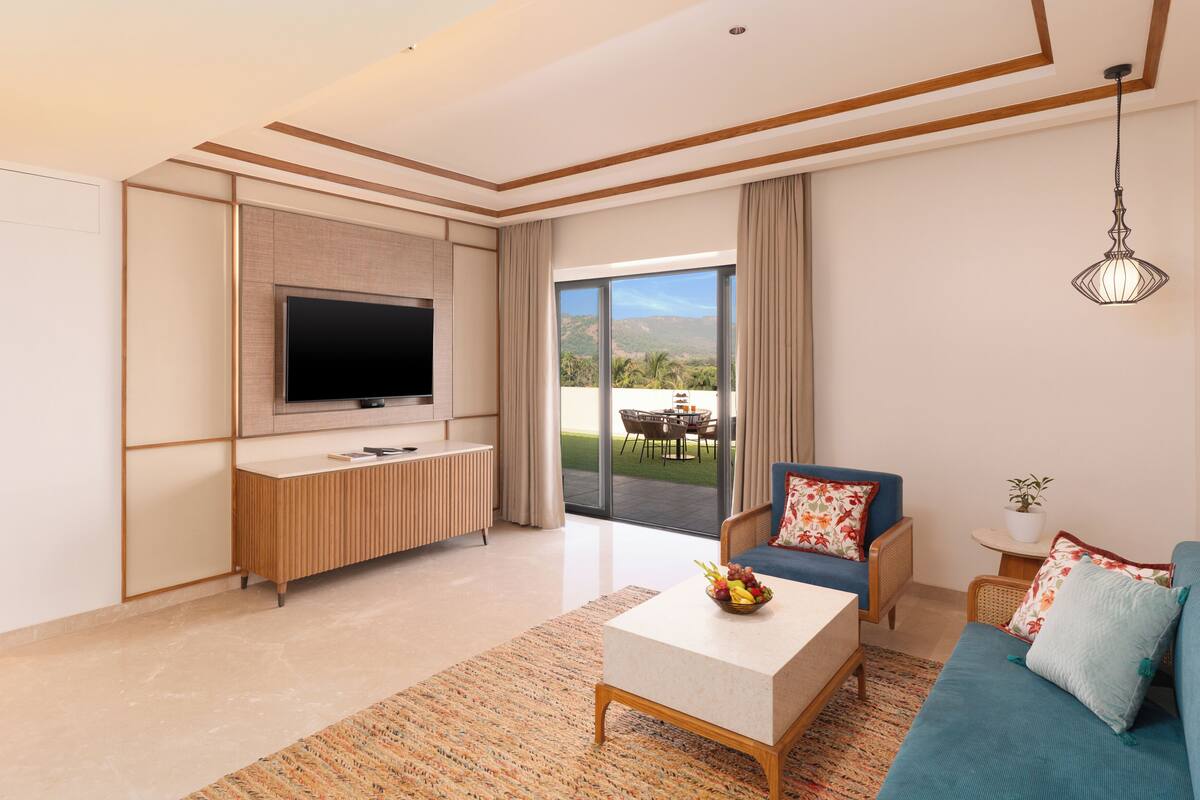 Una sala de estar moderna con una televisión de pantalla plana, un sofá, una mesa de centro y vistas al exterior.