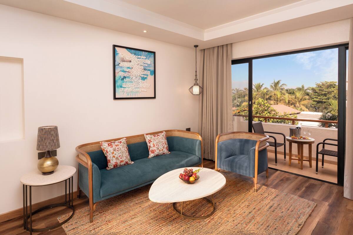 Una sala de estar moderna con un sofá, sillones, una mesa de centro y vistas a un paisaje tropical.