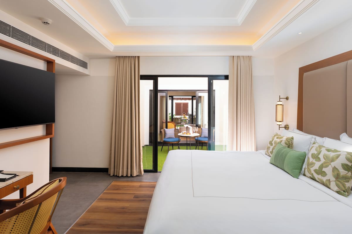 Una habitación de hotel con cama, escritorio, televisor y vista al área de comedor exterior.