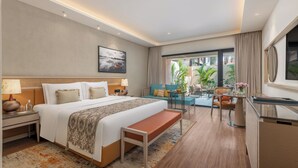 A hotel room with a large bed, a desk, a bench, and a view of the outdoors. - Taj Alibaug Resort & Spa (Alibag)