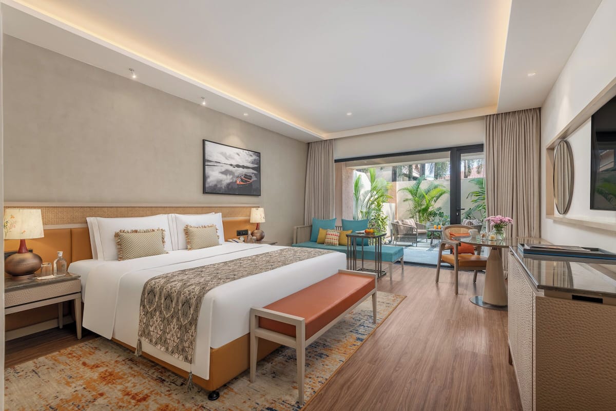 Una habitación de hotel con una cama grande, un escritorio, un banco y vistas al exterior.