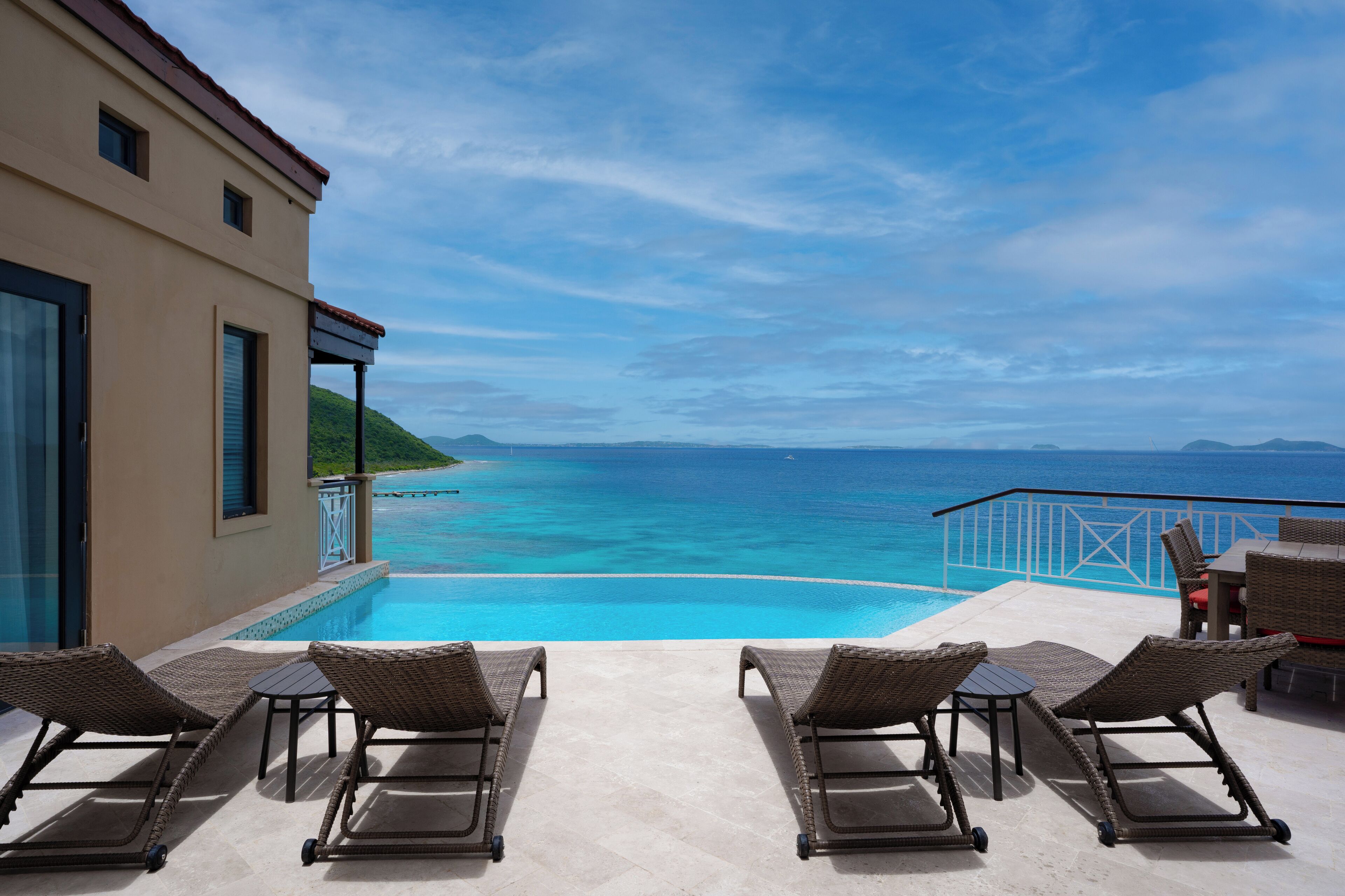 A poolside area with lounge chairs and a view of the ocean.