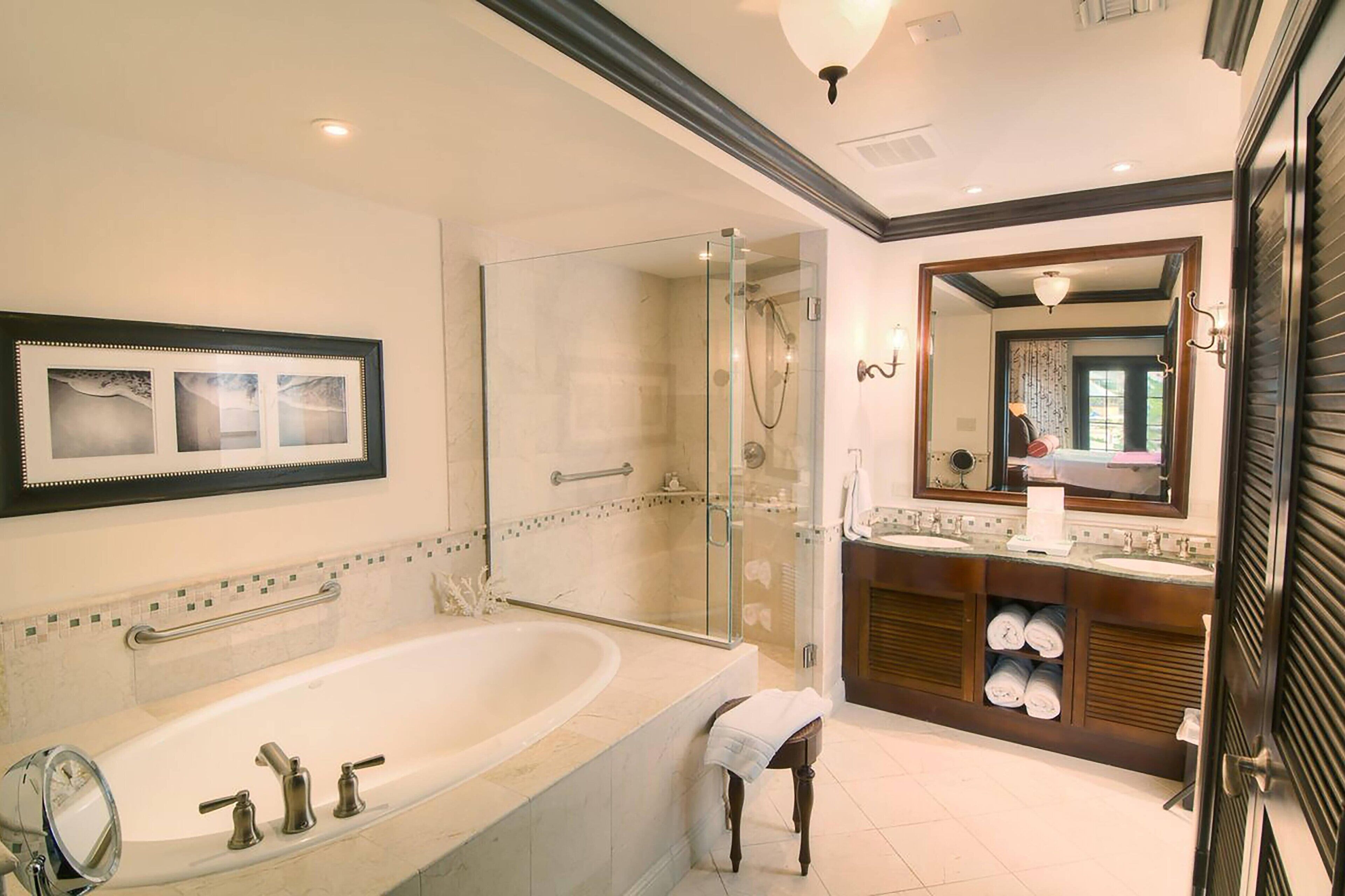 Une salle de bain moderne avec une baignoire sur pieds, une douche à parois de verre et un meuble-lavabo doté d’un miroir et d’un porte-serviettes.