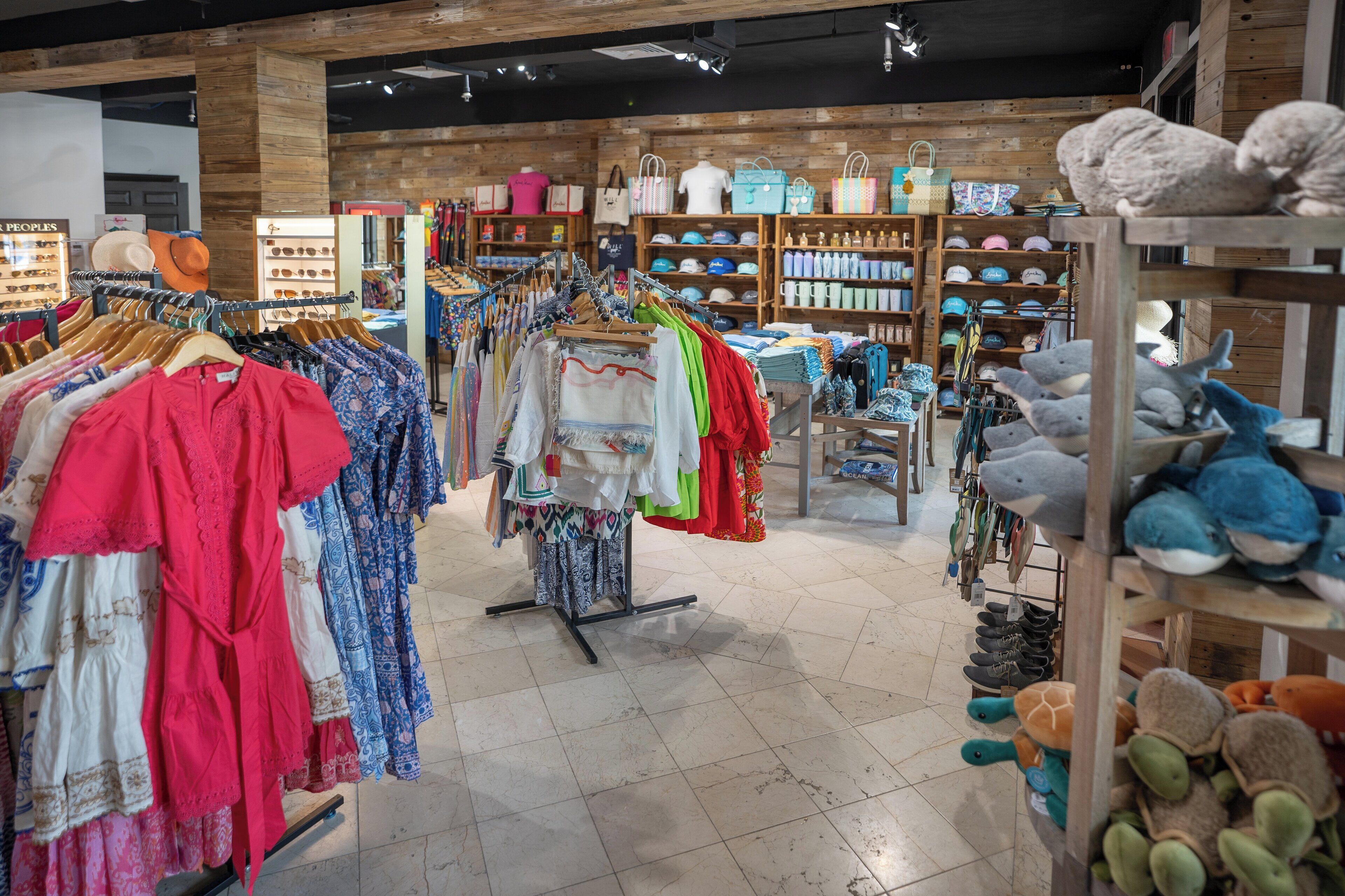 A clothing store with racks of colorful garments and shelves of handbags and shoes.