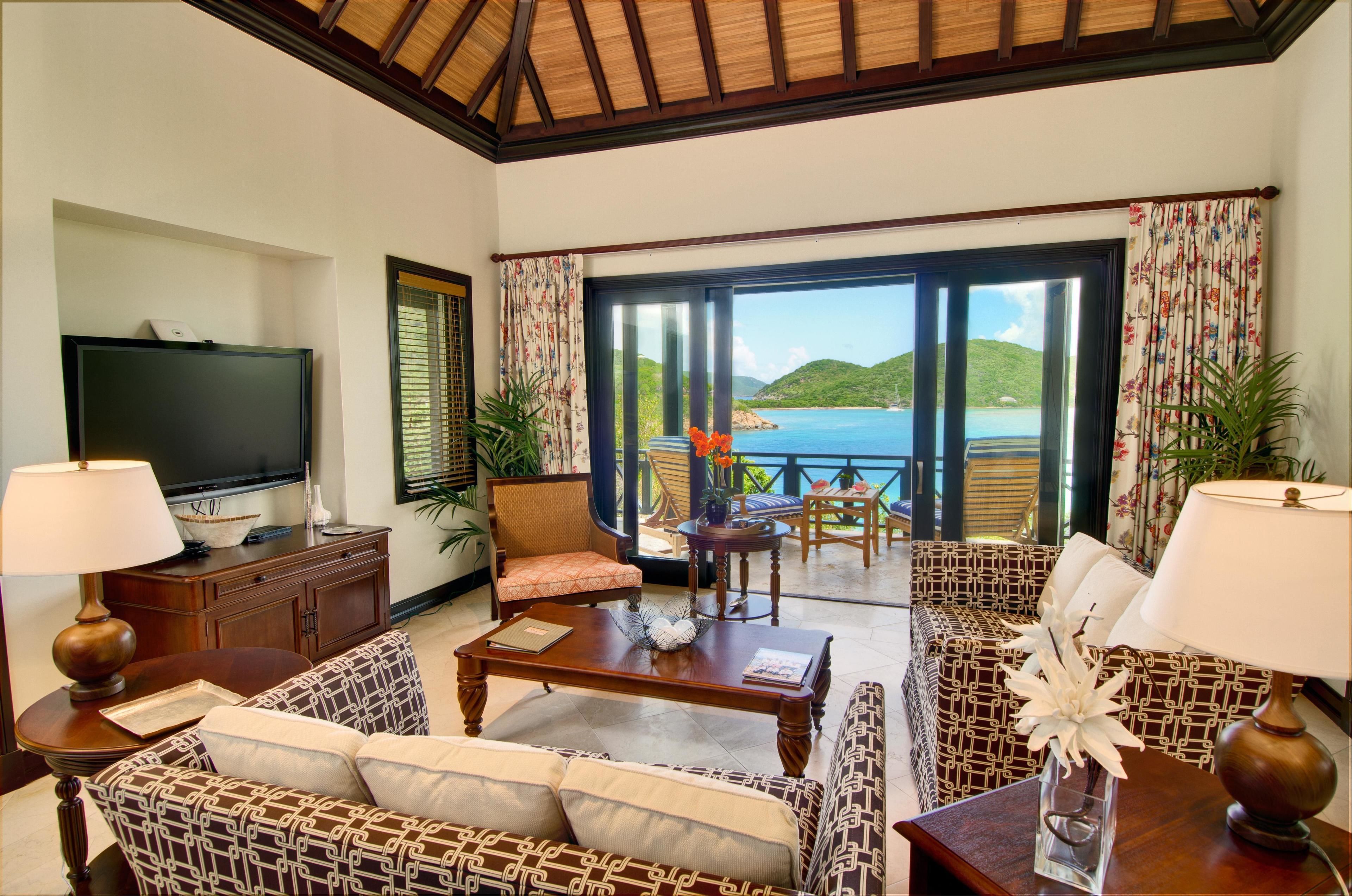 Una sala de estar con televisor, sofás, una mesa de centro y vista al mar.