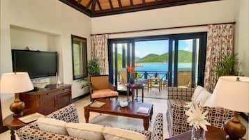 Una sala de estar con televisor, sofás, una mesa de centro y vista al mar.