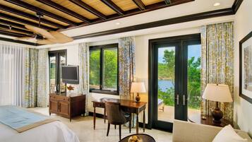 A hotel room with a bed, a desk, a chair, a TV, and a view of the outdoors.