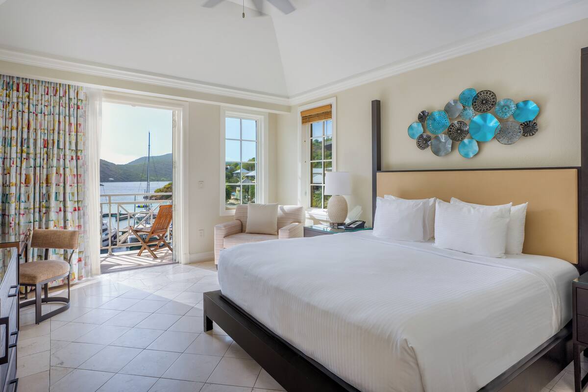 Un dormitorio amplio con una cama grande, un balcón con vistas al mar y un elemento decorativo en la pared.