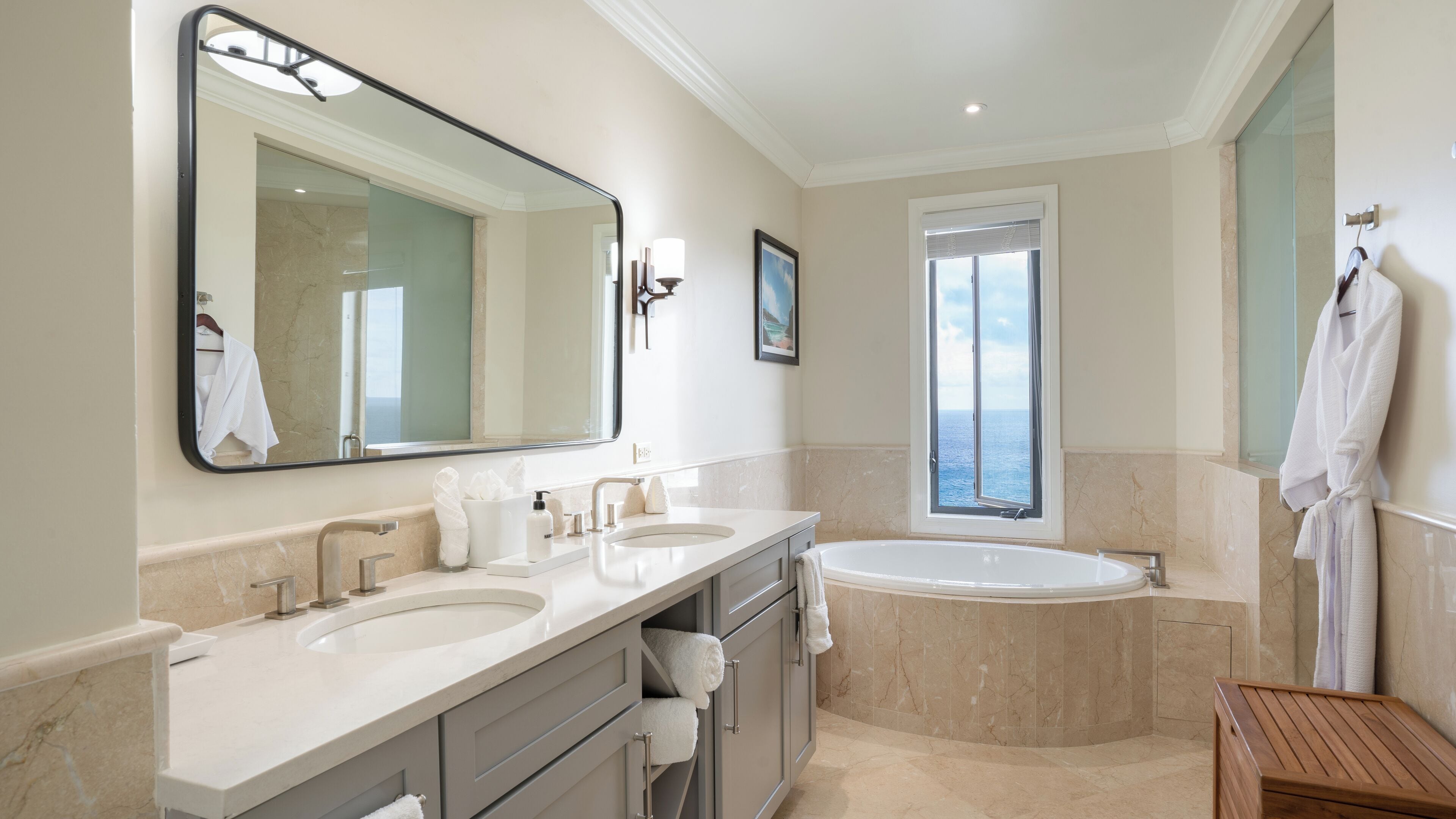 A modern bathroom with two sinks, a large mirror, a bathtub, and a window with a view.