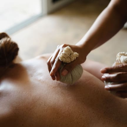 A person receiving a massage with a focus on the hands applying pressure.