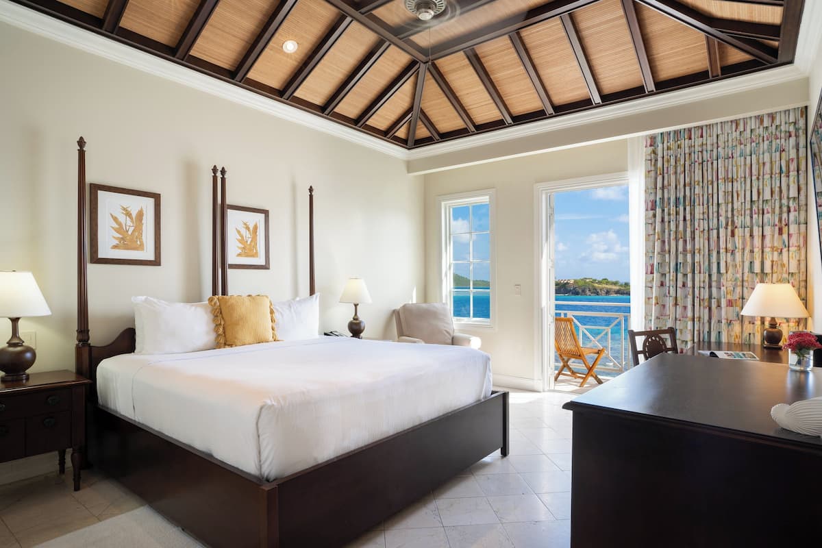 Un dormitorio amplio con una cama grande, un escritorio y vista al mar.