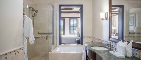 A modern bathroom with a glass-enclosed shower, a bathtub, and two sinks.