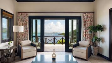 Une pièce avec deux fauteuils, une table basse en verre et une vue sur la mer.