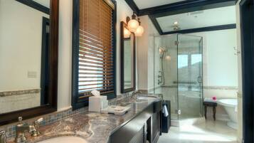 A modern bathroom with a large mirror, dual sinks, a glass shower enclosure, and a vanity with a marble countertop.