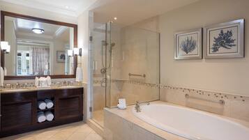 Un baño moderno con una bañera grande, una ducha con mampara de vidrio y un tocador con espejo y toalleros.
