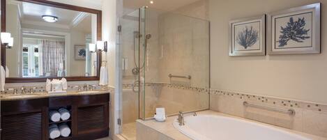 A modern bathroom with a large bathtub, a glass-enclosed shower, and a vanity with a mirror and towel racks.