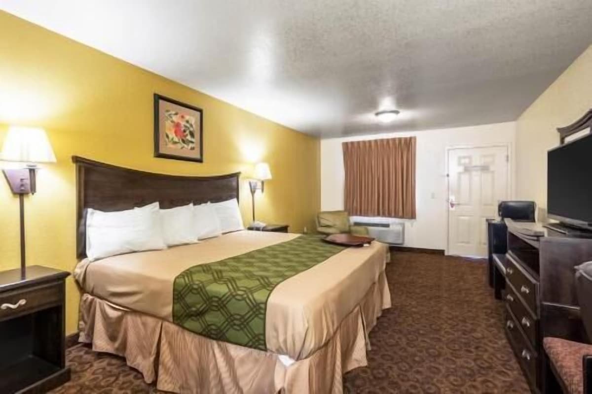 A hotel room with a bed, two bedside tables, a TV, a desk, and a chair.