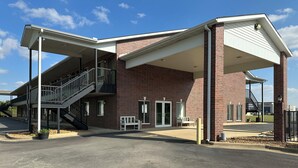 A building with a covered entrance, a staircase, and a bench outside. - The Magnolia Hotel Searcy (Searcy)