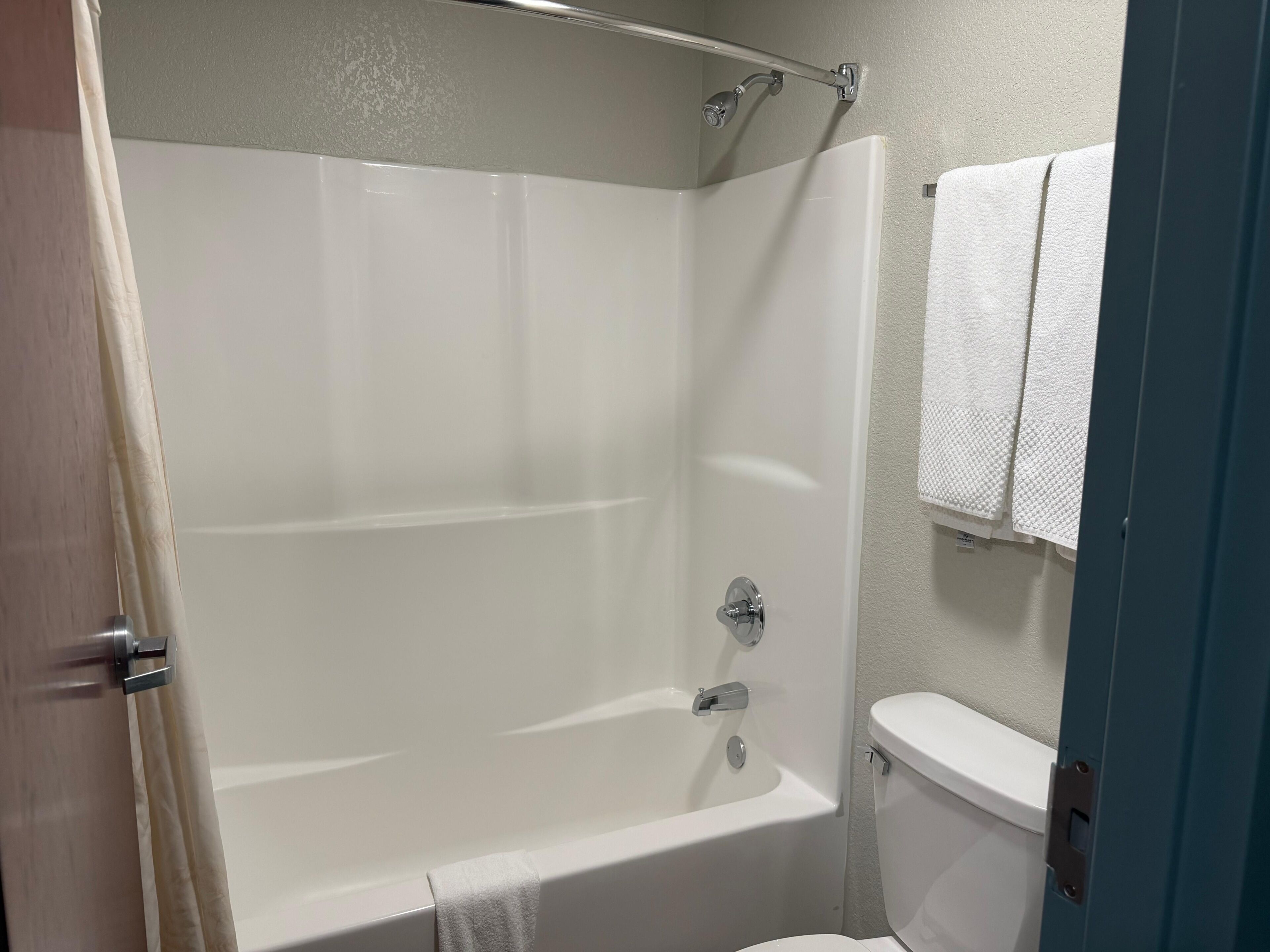 A bathroom with a bathtub, toilet, and a towel rack.