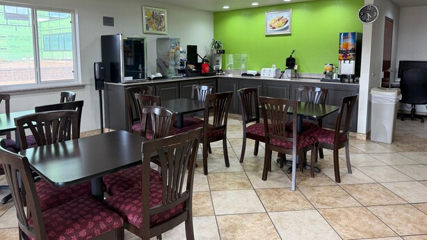 A restaurant with a green wall, a ceiling fan, and a clock. - The Magnolia Hotel Searcy (Searcy)