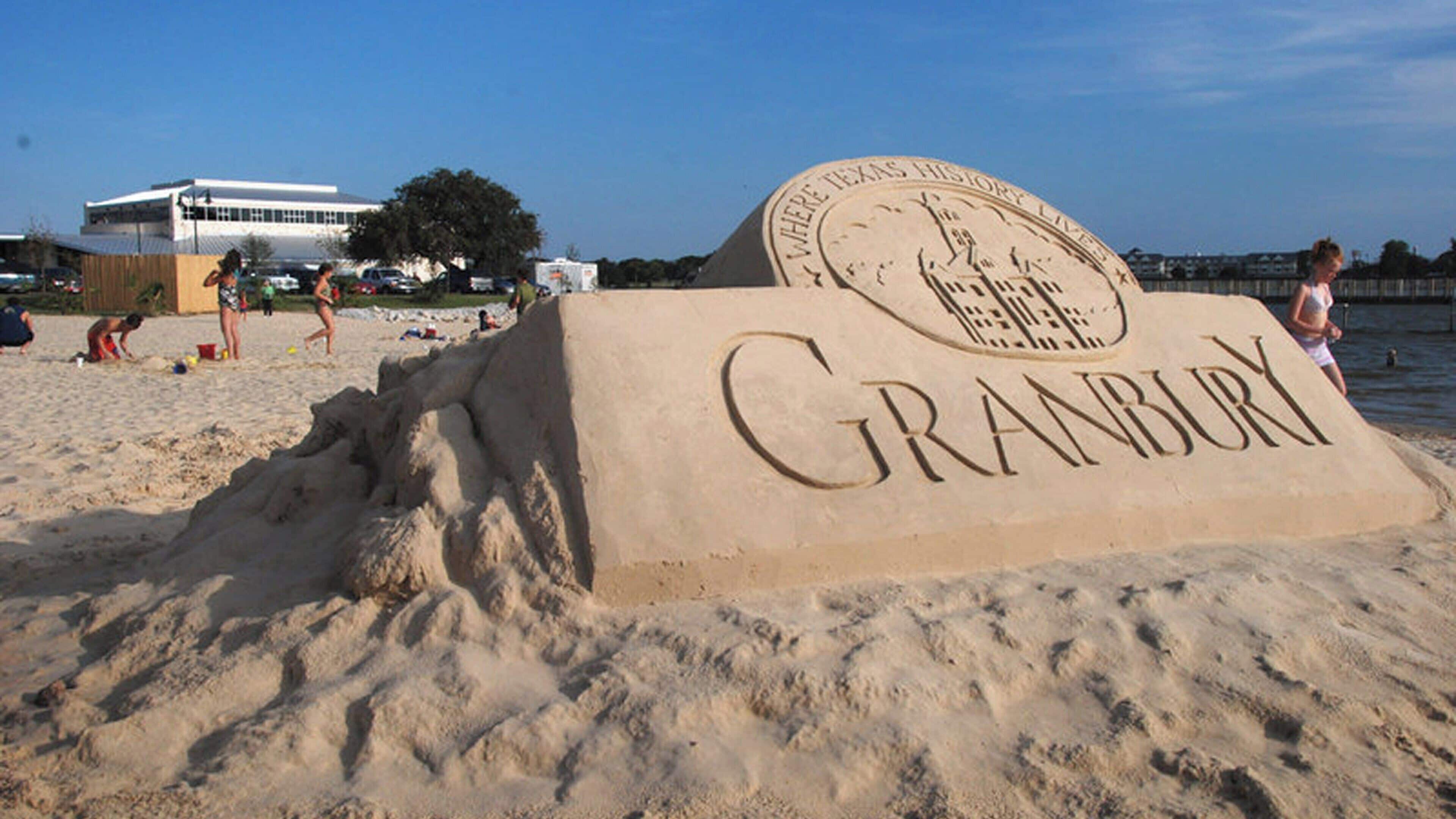 A sand sculpture of 'Granbury' with a circular emblem above it.