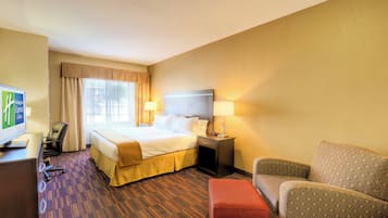 A hotel room with a bed, a desk, a chair, a sofa, and a television.