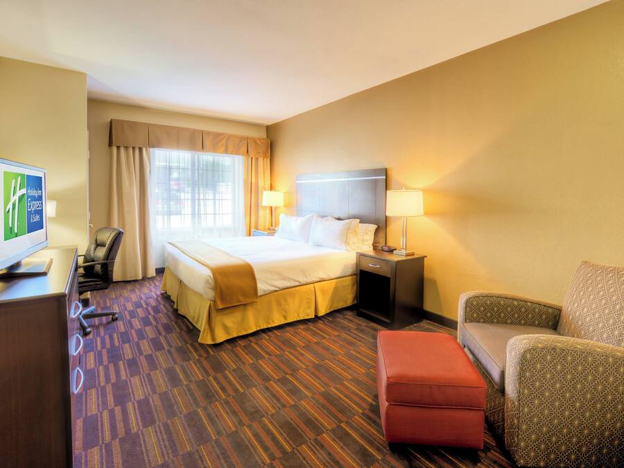 A hotel room with a bed, a desk, a chair, a sofa, and a television.